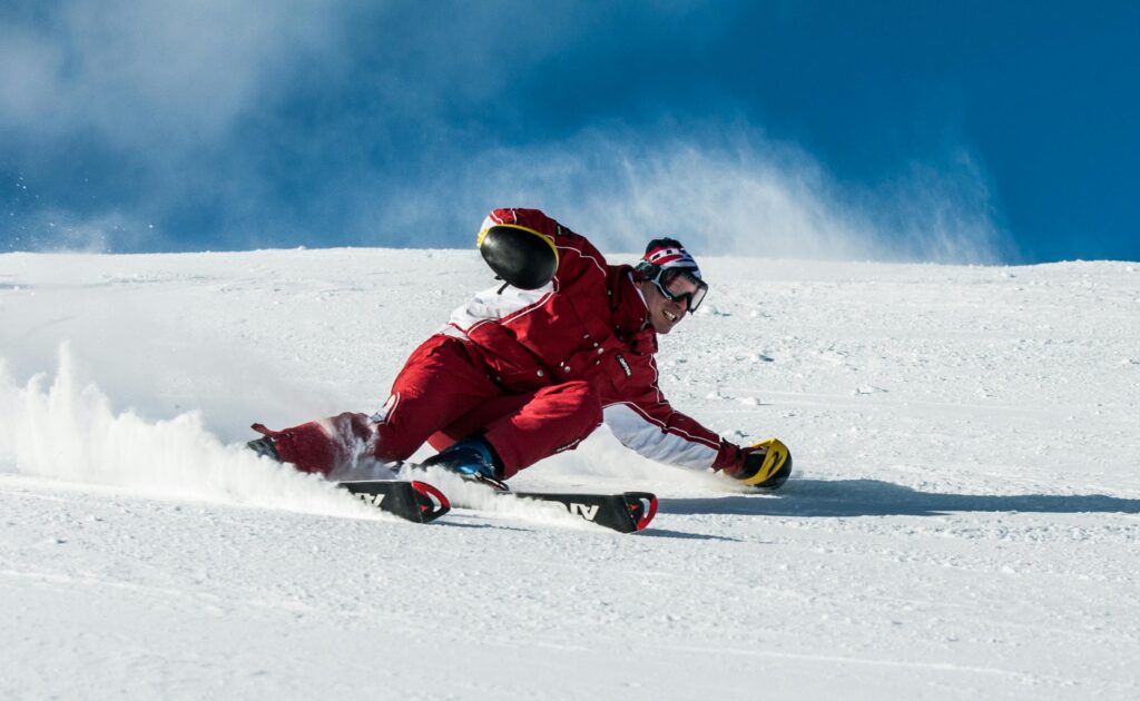 pexels-photo-1271147-1271147 A skier in vibrant red gear skillfully navigates a snowy slope on a sunny day.